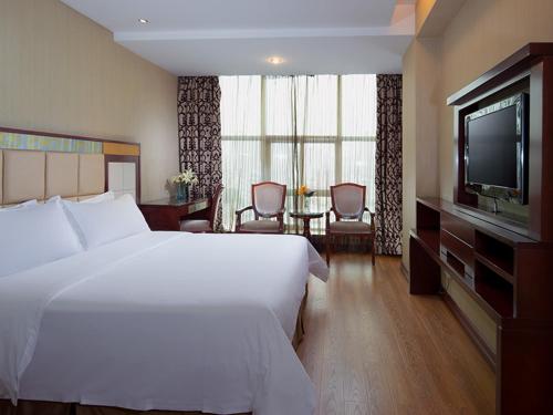 LonggangにあるVienna Hotel in Pinghu Squareの大型ベッドとテレビが備わるホテルルームです。