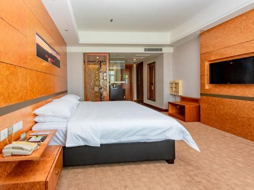 Habitación de hotel con cama grande y TV en Vienna Hotel Dongguan Tangxia Binfen Plaza en Dongguan