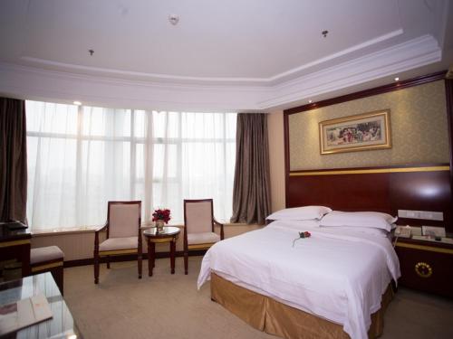 a hotel room with a large bed and two chairs at Vienna Hotel Nanchang Hongcheng in Nanchang