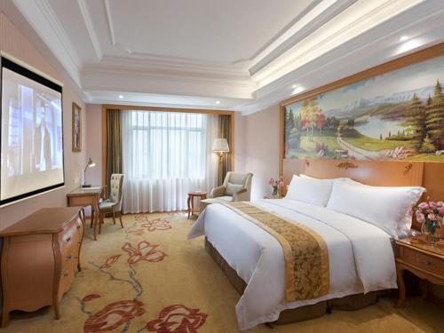una camera d'albergo con un grande letto e un grande dipinto di Vienna Hotel Guangzhou Nanpu Station a Canton