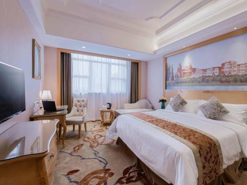 pokój hotelowy z dużym łóżkiem i telewizorem z płaskim ekranem w obiekcie Vienna International Hotel Shenzhen Tian'an Digital City w mieście Longgang