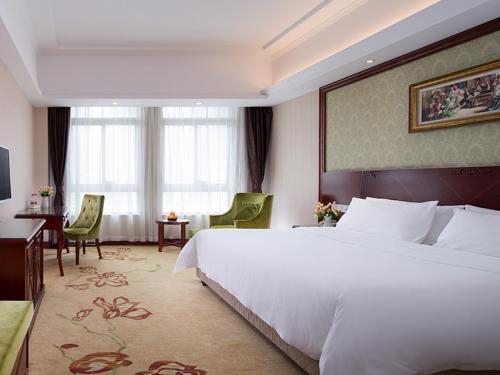 Habitación de hotel con cama blanca grande y escritorio. en Vienna Hotel - Jinzhou Branch, en Guangzhou