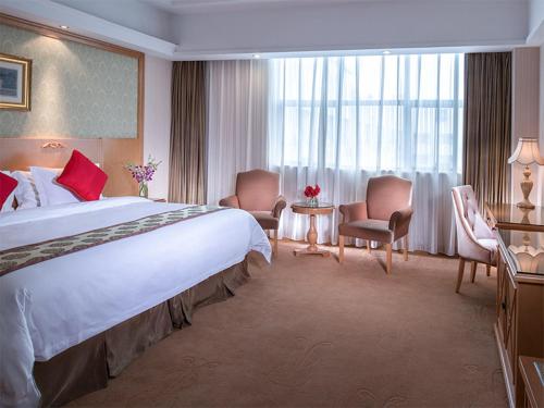 una habitación de hotel con una cama grande y sillas en Vienna International Hotel - Long Hua Wan Zhong Cheng Branch en Bao'an