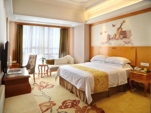 a bedroom with a large bed and a living room at Vienna International Hotel Changsha West Bus Station in Changsha