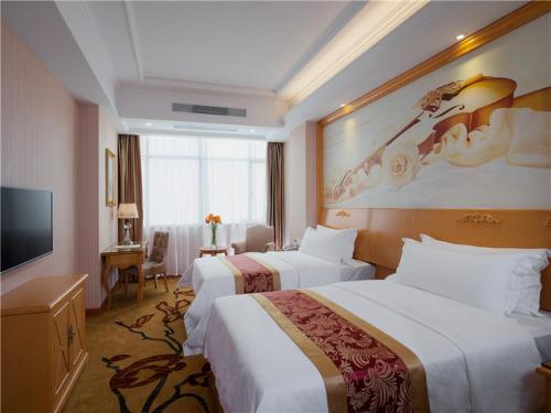 a hotel room with two beds and a television at Vienna Hotel Tianbao Road in Bao'an