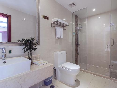 y baño con aseo, lavabo y ducha. en Vienna International Hotel Shenzhen Songgang Wanzhao Square, en Bao'an