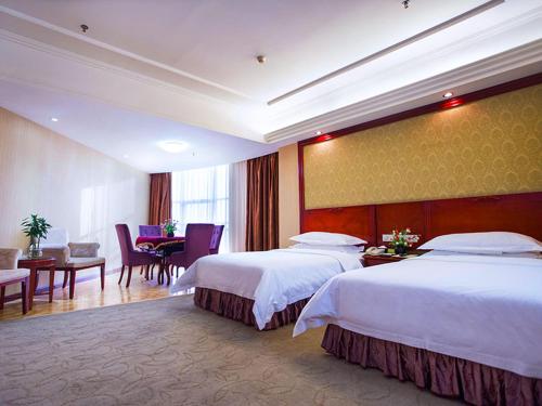 um quarto de hotel com duas camas e uma mesa e cadeiras em Vienna International Hotel Shenzhen Songgang Wanzhao Square em Bao'an