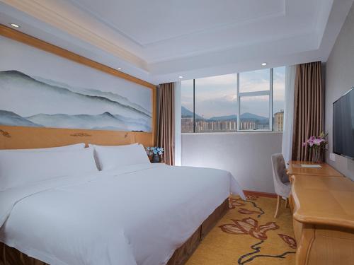 a bedroom with a bed and a desk and a television at Vienna 3 Best Hotel(Guangdong Yangchun Bus Station Shop ) in Yangjiang