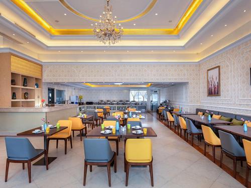 um restaurante com mesas e cadeiras e um lustre em Vienna Hotel Dongguan Mayong Centre Avenue em Dongguan