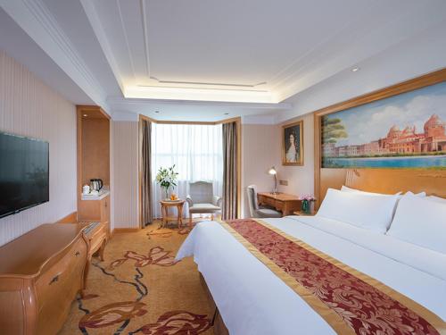 a hotel room with a large bed and a television at Venus International Hotel Shenzhen Gongming Tianhong in Xitian