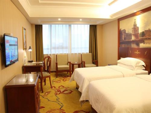 Vienna International Hotel Ningbo South Huancheng Road في نينغبو: غرفه فندقيه سريرين وتلفزيون