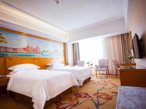 a hotel room with two beds and a painting on the wall at Vienna Hotel Jiangxi Yichun City Hall in Yichun