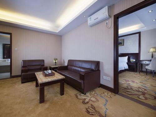 a living room with a couch and a table and a bed at Vienna Hotel Shenzhen Shangjin Center in Bao'an