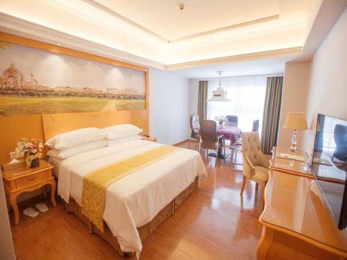 a hotel room with a bed and a large painting on the wall at Vienna Hotel Guangdong Huizhou Jiangbei Sanxin in Huizhou