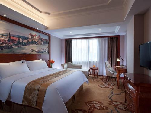 um quarto de hotel com uma cama grande e uma televisão em Vienna International Hotel Shaoguan Fengcailou em Shaoguan