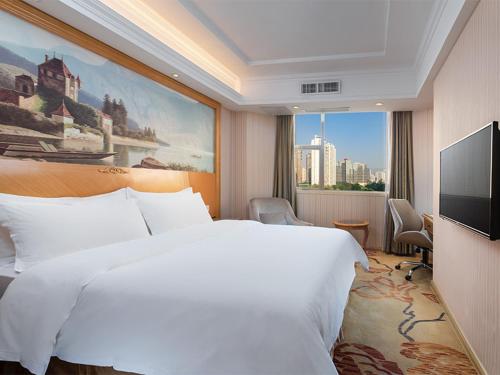 een slaapkamer met een groot wit bed en een groot schilderij bij Vienna Hotel Shenzhen Honghu in Shenzhen