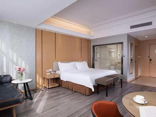 a bedroom with a large bed and a living room at Vienna Hotel Zhongshan XiaoLan in Zhongshan