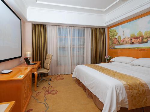 Habitación de hotel con cama grande y escritorio. en Vienna Hotel Shanghai Hongqiao National Exhibition Center Huaxin en Qingpu
