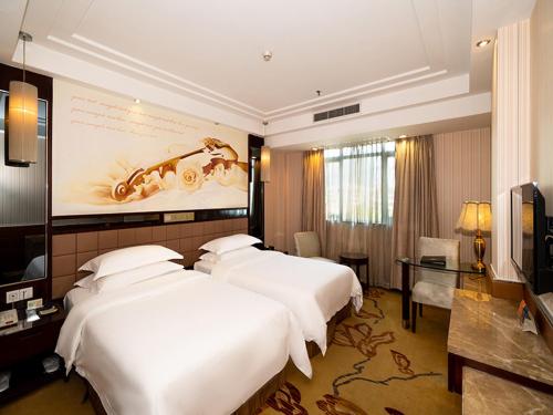 肇慶市にあるVienna Hotel Zhaoqing Qixingyanpaifangのベッド3台とテレビが備わるホテルルームです。