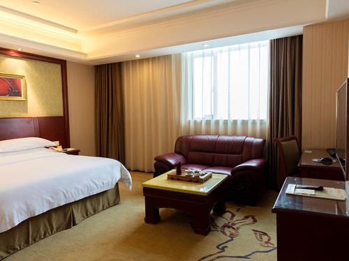 Vienna Hotel Foshan Jihua Road في فوشان: غرفه فندقيه بسرير وكرسي