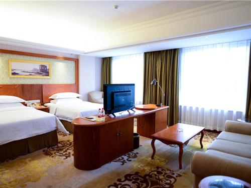 a hotel room with two beds and a desk with a computer at Vienna Hotel Xinjiang Yining Shanghai City in Yining