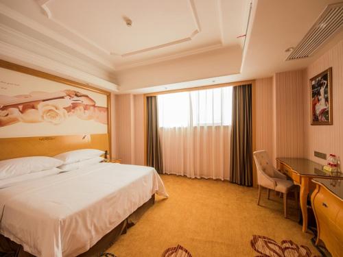 a hotel room with a large bed and a desk at Vienna International Hotel(Chenzhou Wuling Square Shop) in Chenzhou