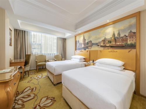 a hotel room with two beds and a painting on the wall at Vienna Hotel (Quanzhou Bus Station) in Quanzhou