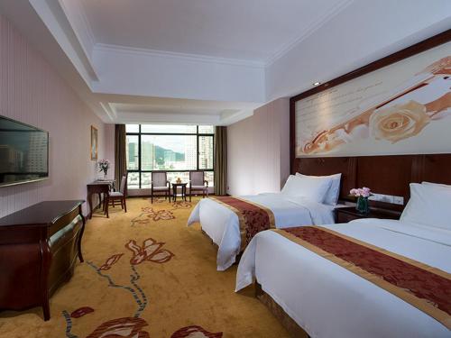 a hotel room with two beds and a television at Vienna International Hotel Jieyang Jieyanglou in Jieyang