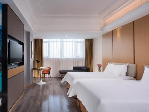 a hotel room with a large bed and a television at Vienna Hotel Zhongshan XiaoLan in Zhongshan