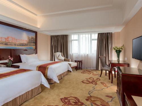 a hotel room with two beds and a television at Vienna Hotel Foshan Nanhai City Square in Foshan