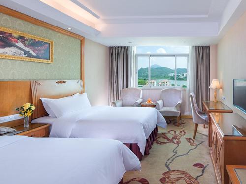 um quarto de hotel com duas camas e uma televisão em Vienna 3 Best Hotel Shenzhen Henggang Cuihu Shangzhuang em Longgang