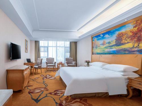 a bedroom with a large bed and a large painting on the wall at Vienna Hotel(Anqing Guangcai Seven-street) in Anqing