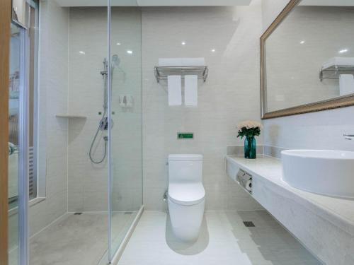 W łazience znajduje się prysznic, toaleta i umywalka. w obiekcie Vienna International Hotel Shenzhen Tian'an Digital City w mieście Longgang