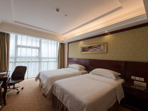 um quarto de hotel com duas camas e uma secretária e uma janela em Vienna Hotel Shanghai Hongqiao Airport Center em Xangai