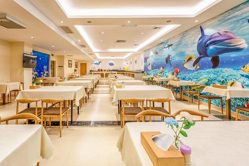 restauracja ze stołami i krzesłami oraz wielorybim malowidłem w obiekcie Vienna International Hotel Guangdong Zhengjiang Renming Avenue Middle Road w mieście Zhanjiang