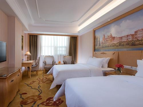 una camera d'albergo con due letti e una televisione di Vienna International Hotel Shenzhen Longhua Center a Bao'an
