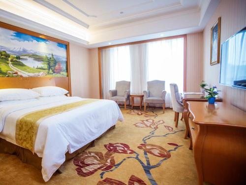 a hotel room with a large bed and a desk at Vienna International Hotel Hangzhou Zhuantang Art School in Wenyan