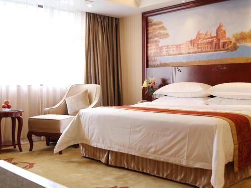 a hotel room with a large bed and a chair at Vienna Hotel Foshan Nanhai City Square in Foshan
