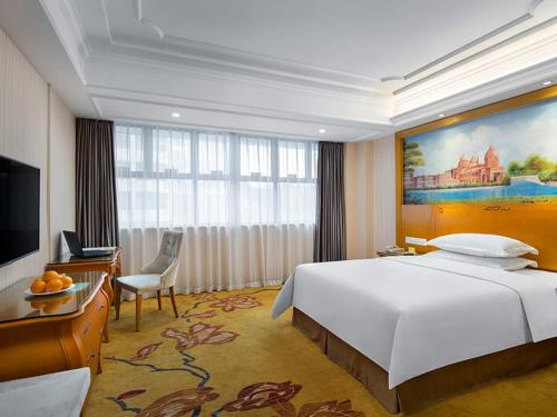 ein Hotelzimmer mit einem großen Bett und einem TV in der Unterkunft Vienna Hotel Changsha Gaoxin Lugu Park in Changsha