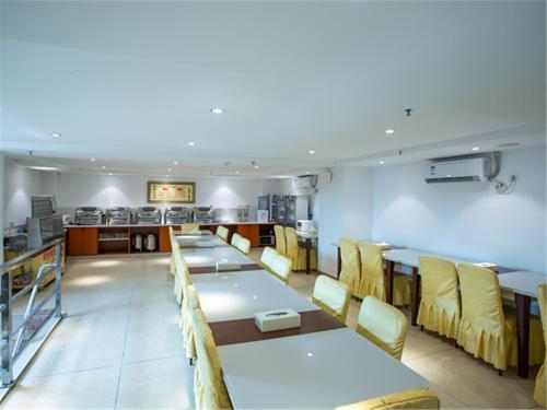 una sala da pranzo con tavoli lunghi e sedie gialle di Vienna Hotel Guangzhou Nanpu Station a Canton