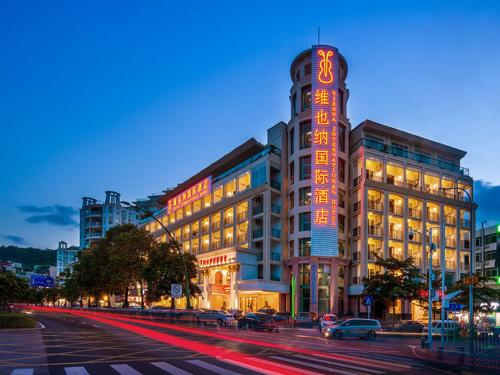 un bâtiment avec des panneaux de néon sur son côté dans l'établissement Vienna International Hotel Shenzhen Dameisha, à Shenzhen