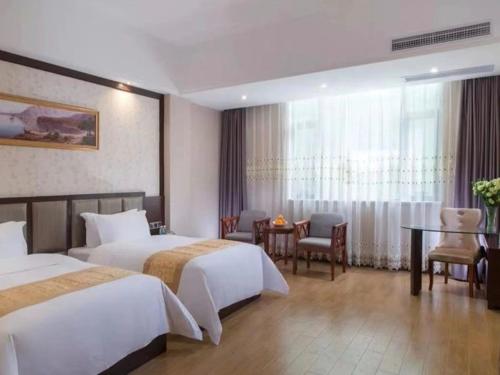 um quarto de hotel com duas camas e uma mesa em Vienna International Hotel Jieyang Chaoshan Airport em Jieyang