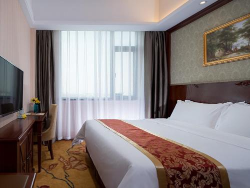 a hotel room with a large bed and a desk at Vienna Hotel Dongguan Qiaotou in Qiaotou