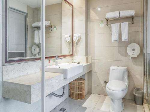 a bathroom with a sink and a toilet and a mirror at Vienna Hotel Wuxi Wangzhuang Road in Wuxi