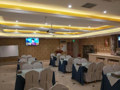 a banquet hall with tables and chairs and a screen at Vienna Hotel Xinjiang Yining Shanghai City in Yining