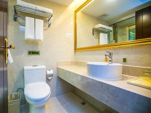 La salle de bains est pourvue d'un lavabo, de toilettes et d'un miroir. dans l'établissement Vienna Hotel Nanjing Longjiang, à Nankin