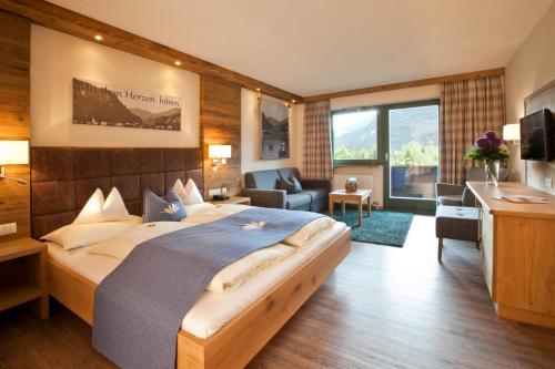 a bedroom with a large bed and a living room at Seehotel Brunner in Walchsee