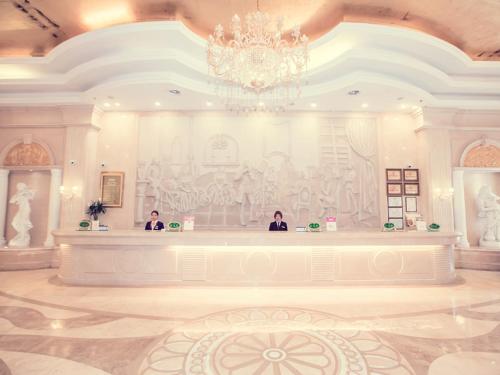 two people sitting at a counter in a large room at Vienna Hotel Rugao Zhengxiang Square in Rugao