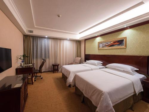 a hotel room with two beds and a television at Vienna Hotel Shanghai Hongqiao Airport Center in Shanghai