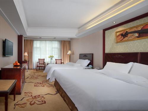 a hotel room with two beds and a table and chairs at Vienna International Hotel Guilin Zhongshan Road in Guilin